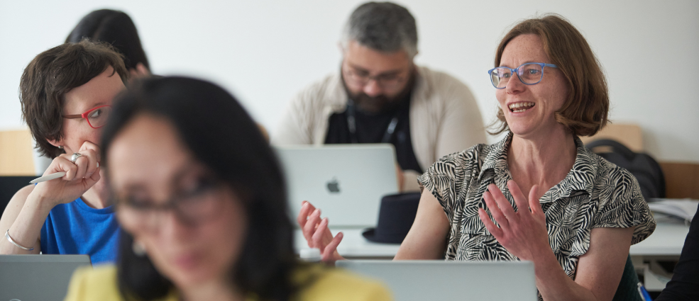 Woman wearing blue glasses speaking in the audience during an ECPR panel